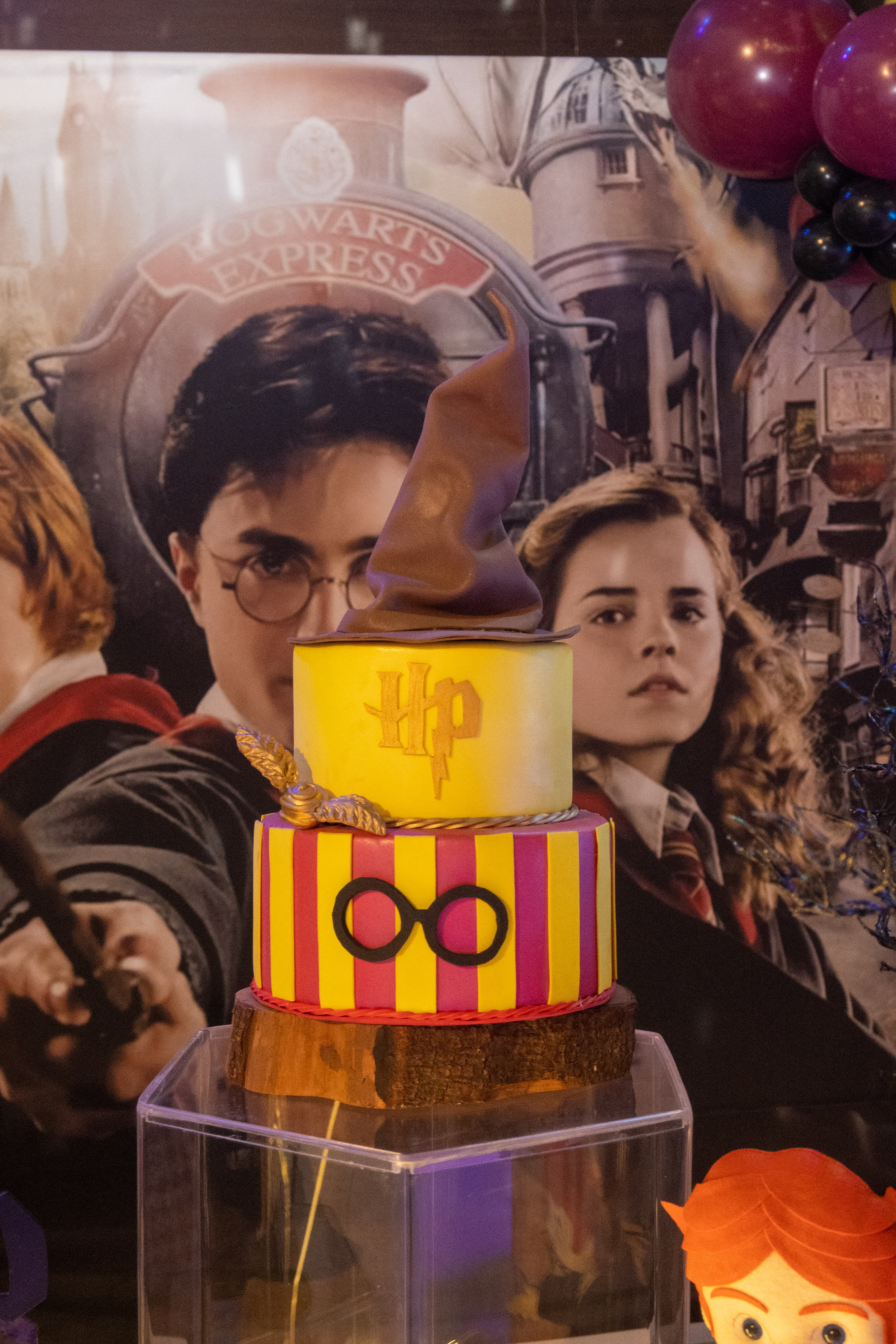 Isabella com varinha mágica em frente ao cenário temático